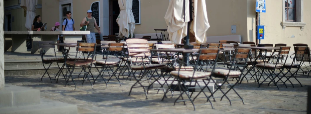 several folding chairs are lined up outside with open umbrellas