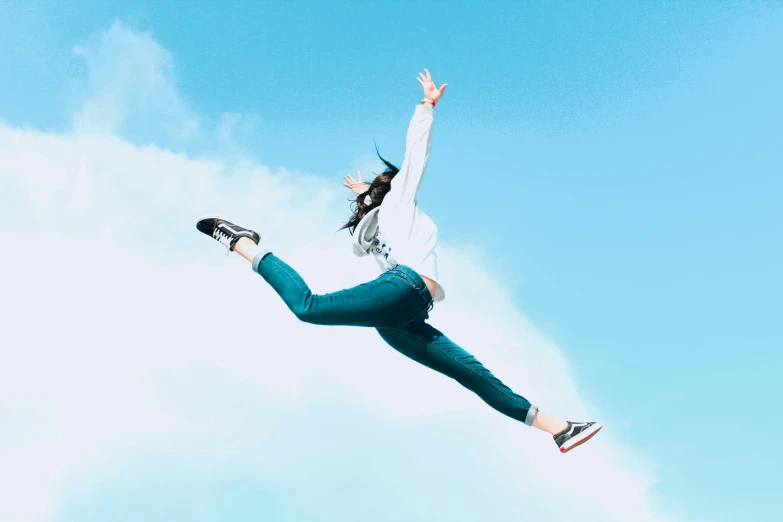 a woman flying through the air while wearing a jacket and jeans