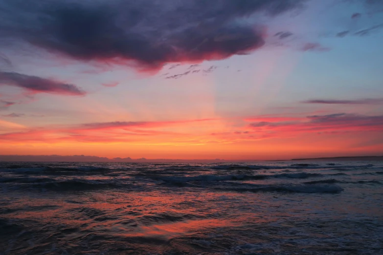 a cloudy sunset over the ocean and ocean wave