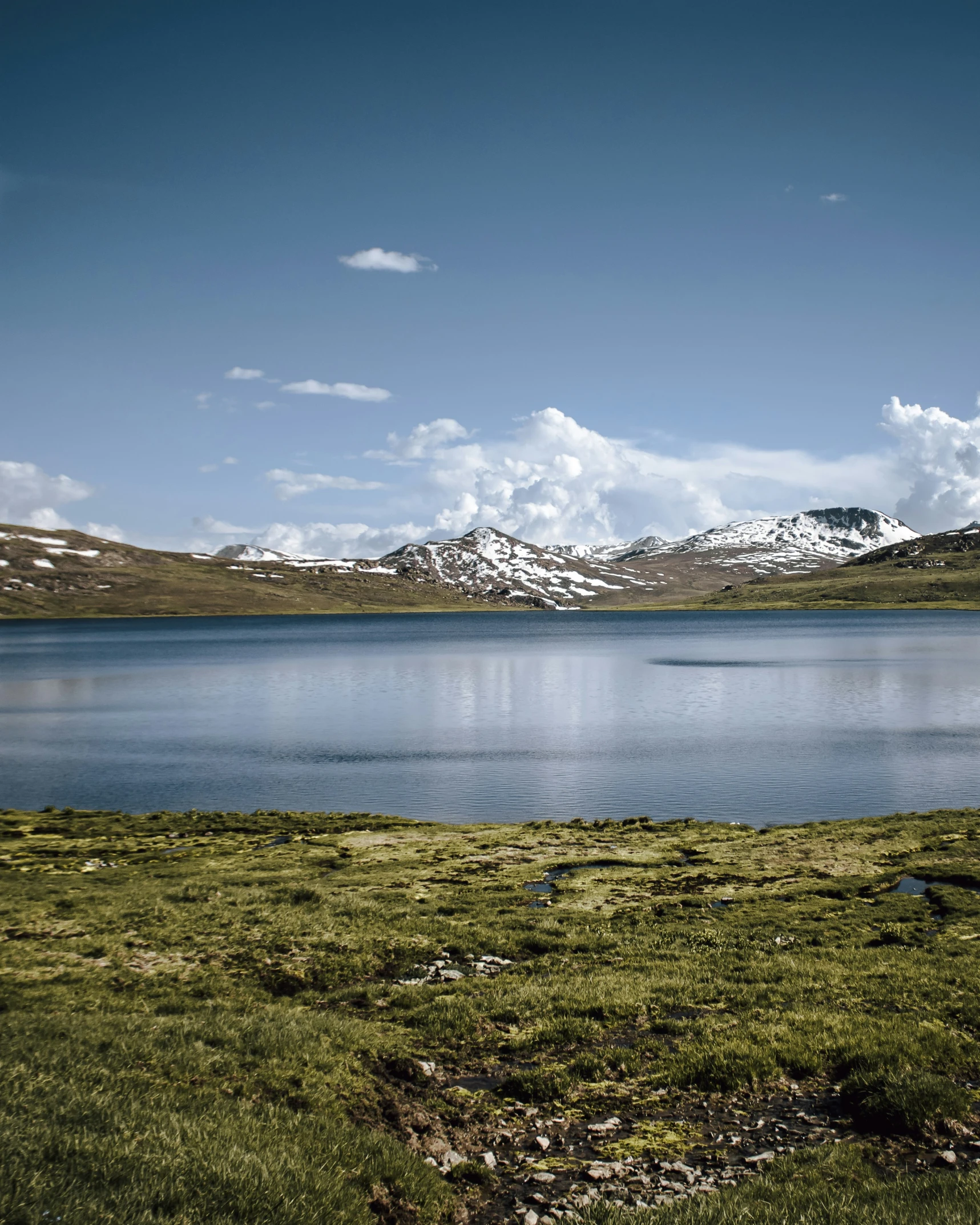 a mountain with snowy peaks next to a lake