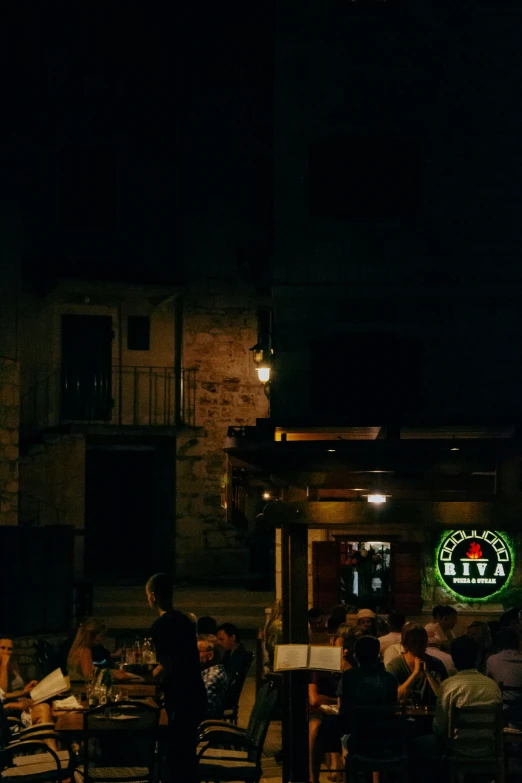 people eating and drinking outside of a restaurant at night