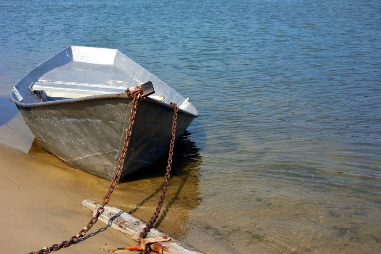 small boat tied up on the sand near the ocean