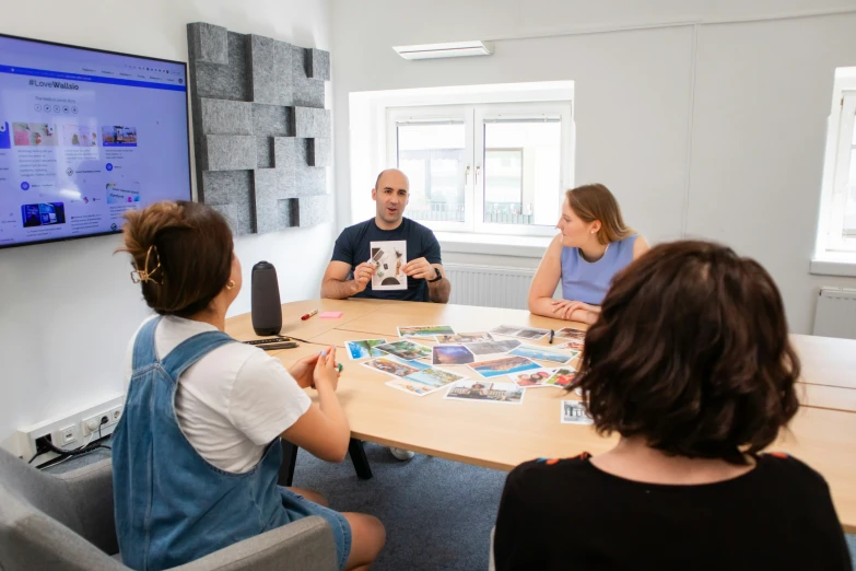 four people sitting around a table playing monopoly on a tv