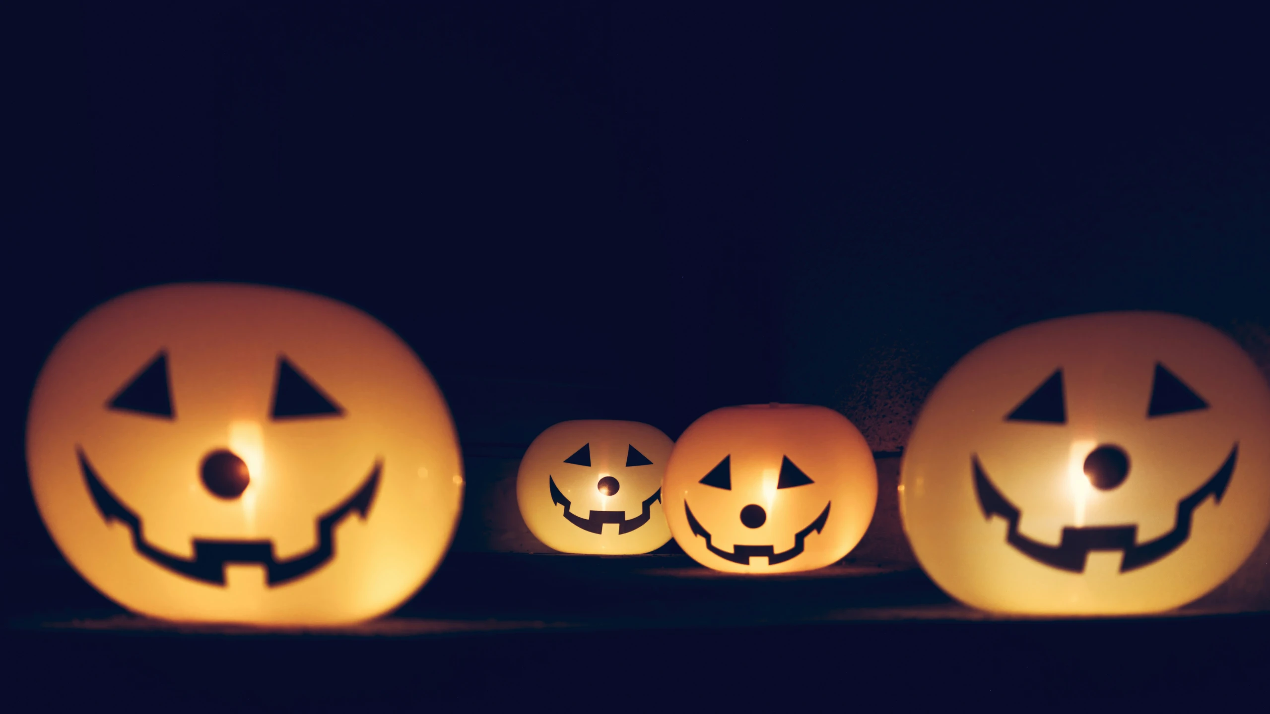 three pumpkins lit up in the dark with jack o lantern faces