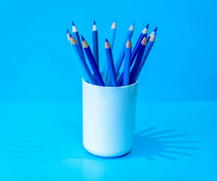 many pencils are in the holder, against the blue background