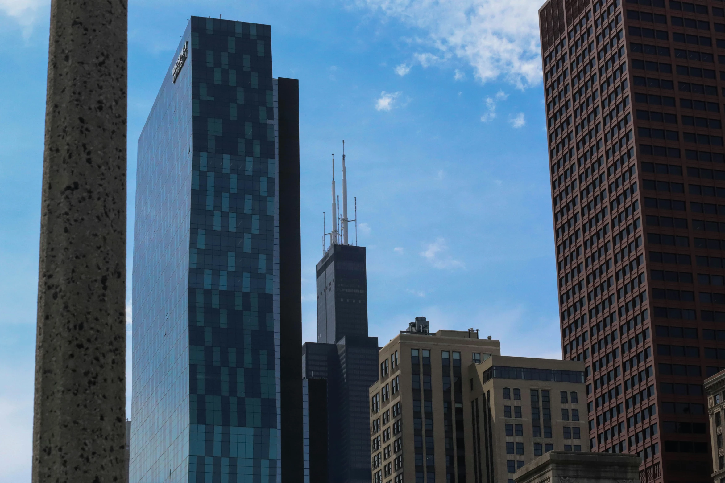 the skyscrs of different buildings are surrounded by clear blue skies