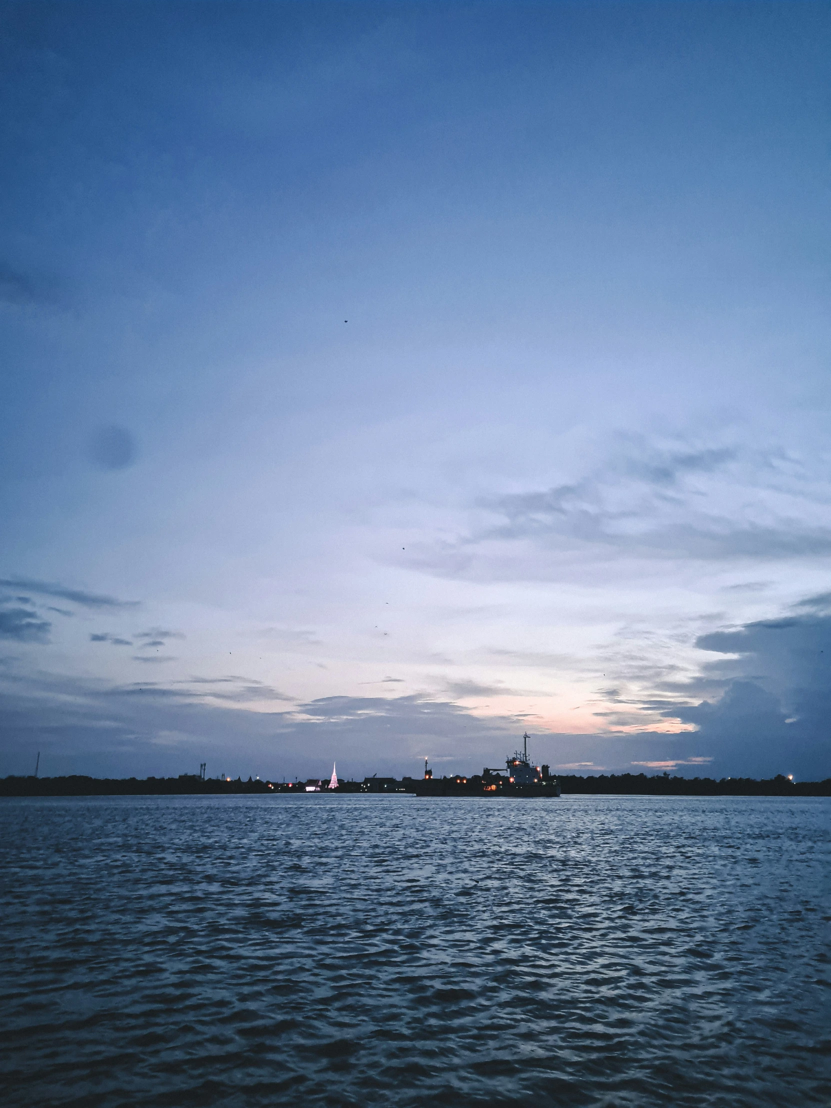 a body of water with clouds and a sailboat