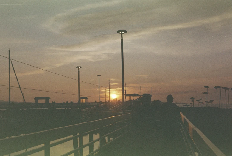 the sun is setting over a park with lots of lights