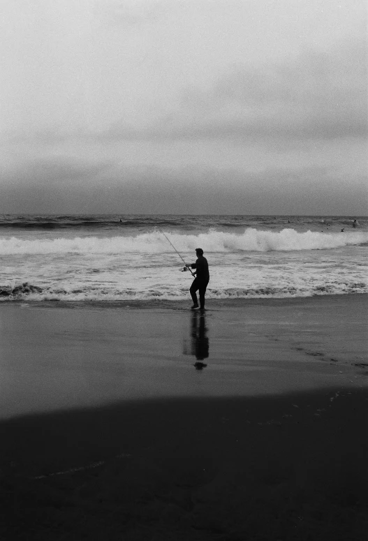 a person with a surfboard on the beach by water