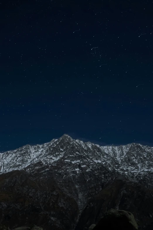 the mountain is in dark skies with stars above it