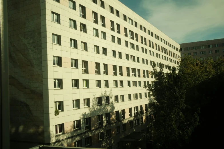 a building with many windows has trees and a street in front of it