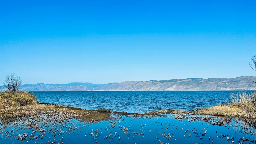 some water and dirt with mountains in the background