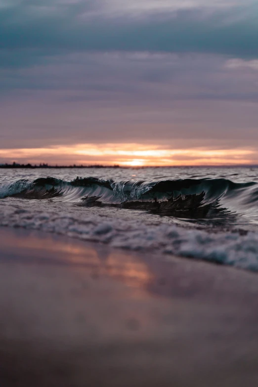 the sun is going down over the water at the beach