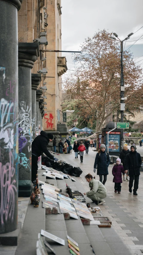 people are walking along a wall with some books on it