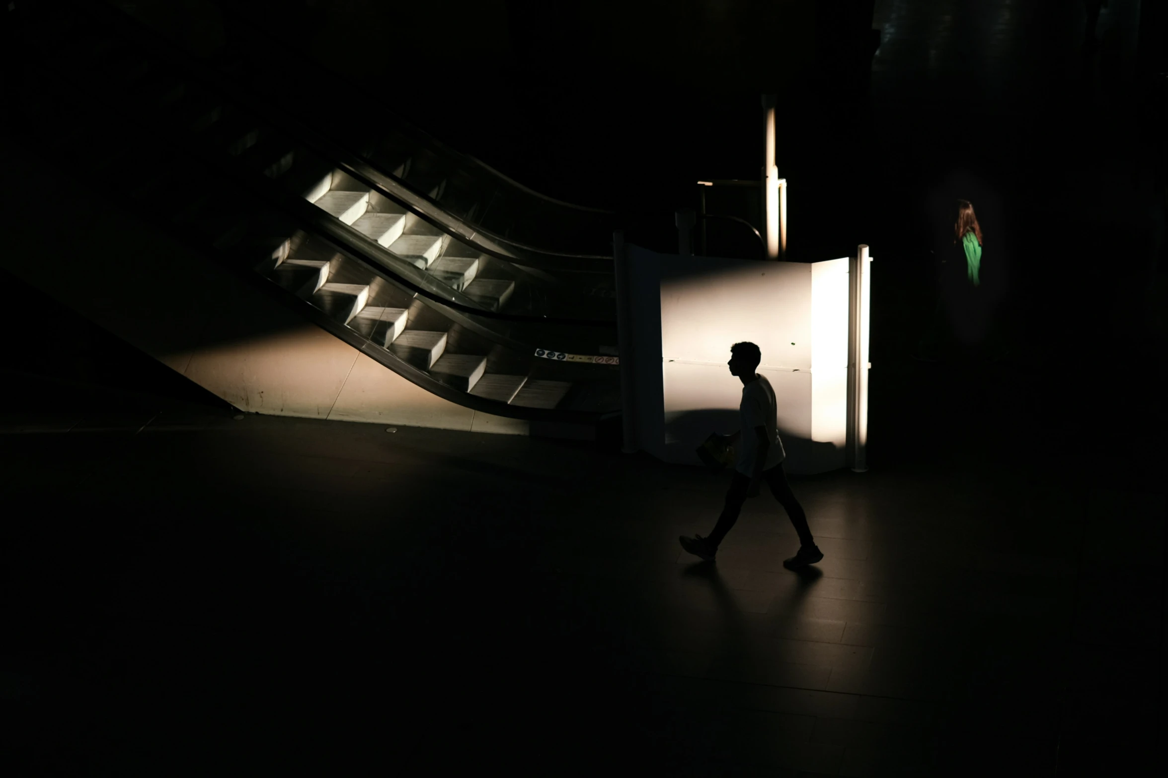 silhouette of a man walking down the street under the light from the stair