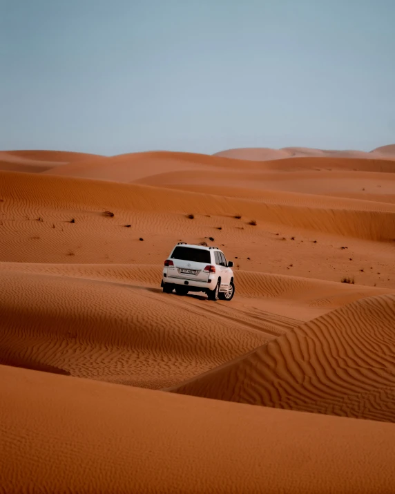 a small vehicle driving through the desert in its natural environment