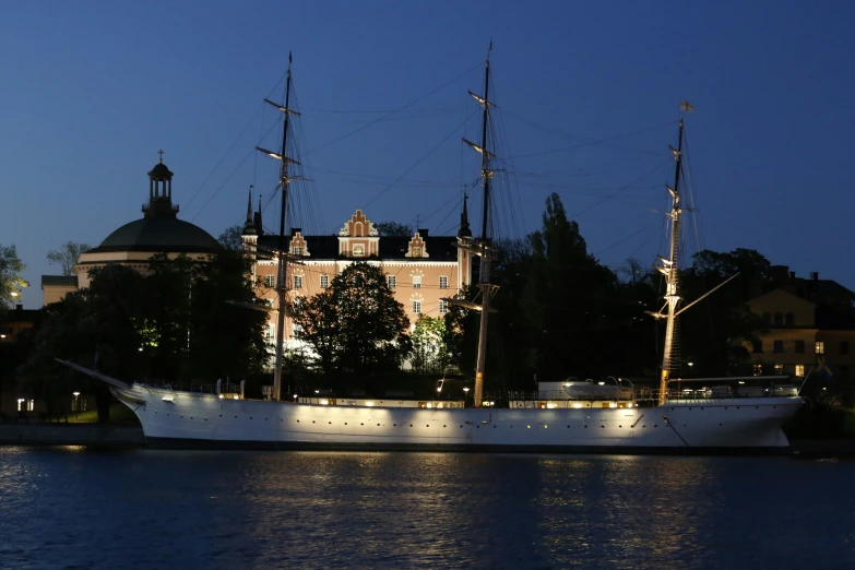 a large white boat traveling along a river at night