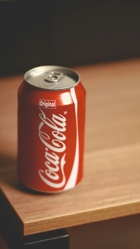 a can of coca cola sitting on a wooden table