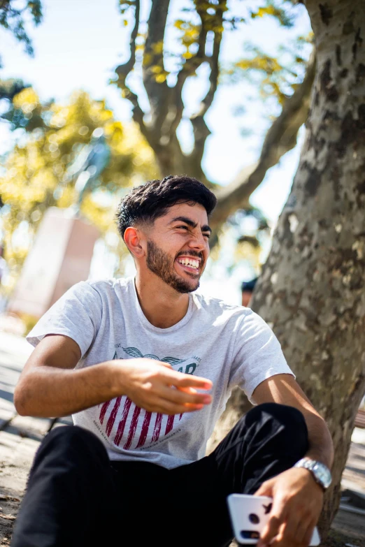 a smiling man is sitting on the ground while holding a frisbee