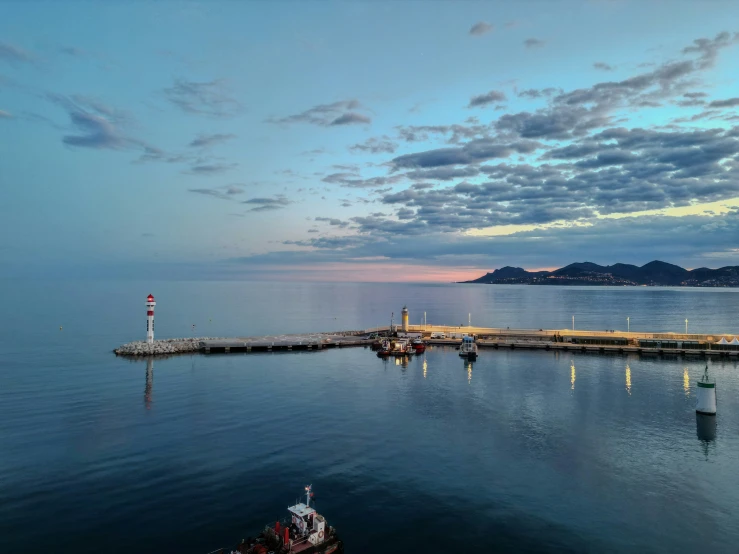 an ocean with a boat and a light house at dusk