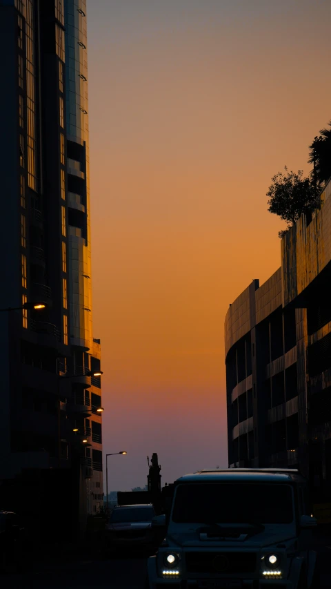 an orange and yellow sky, with cars driving down a street