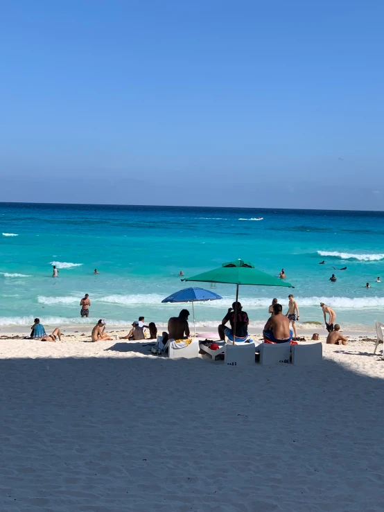 people sitting on a bench on a beach and blue waters
