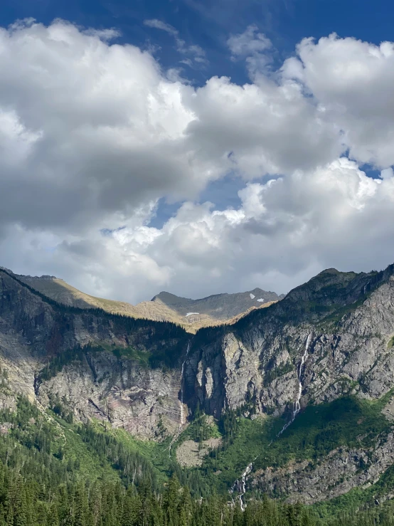 a scenic view of some mountains with green trees in front