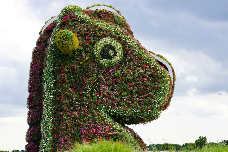 a giant green dog statue covered in flowers