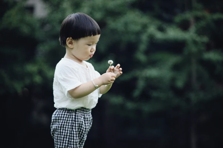 a young child holding a flower while looking down