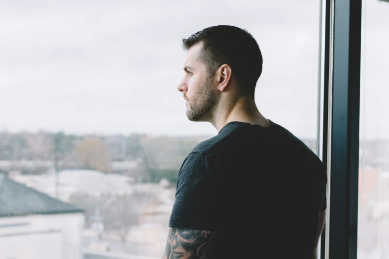 a man in black shirt looking out of window