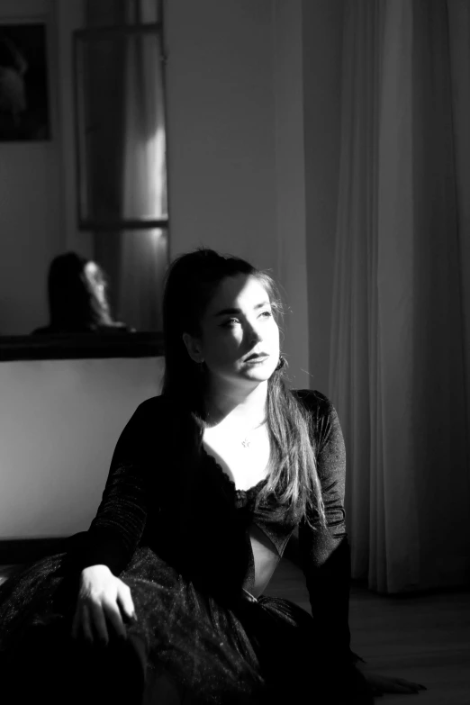 a girl in a dark room sitting on the floor