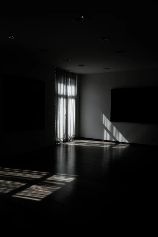 a dark room with an open window with light coming through the windows