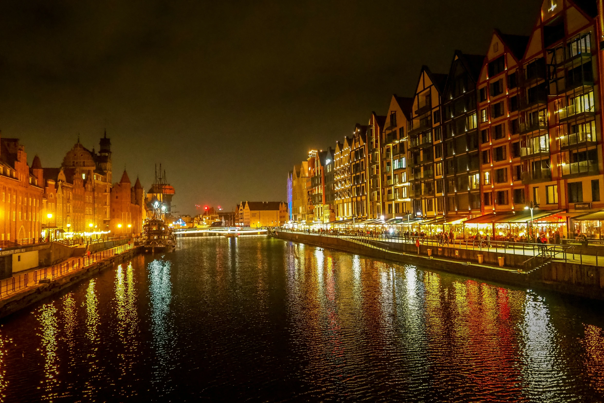 lights on buildings line the water and buildings near a river