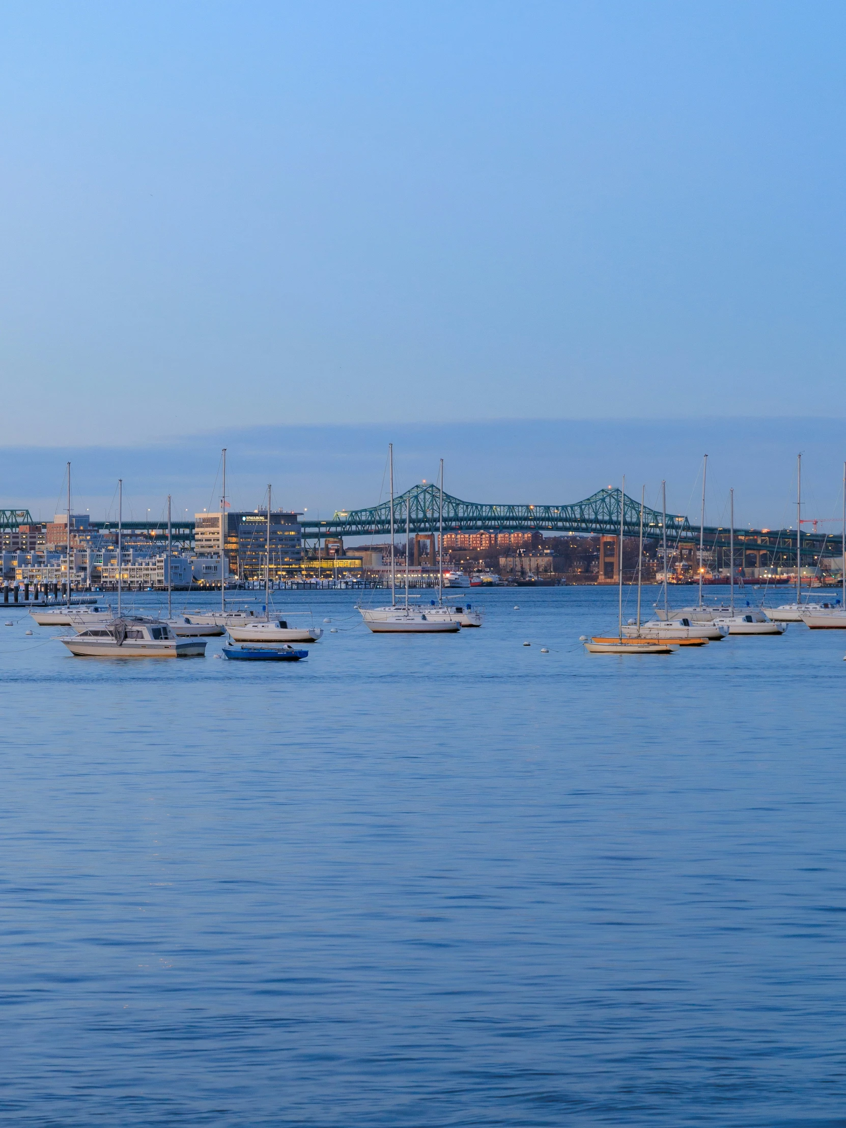 several boats are sitting on the water near the bridge