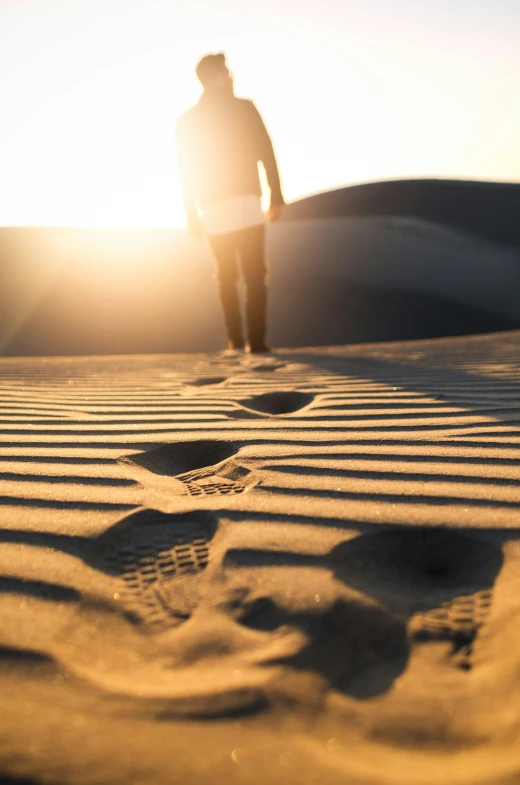 a lone man standing on the sand near the ocean