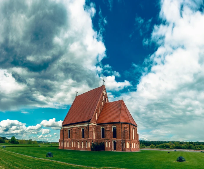 an old red brick church sitting on top of a lush green field