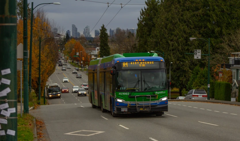 a city bus on a road with cars behind it