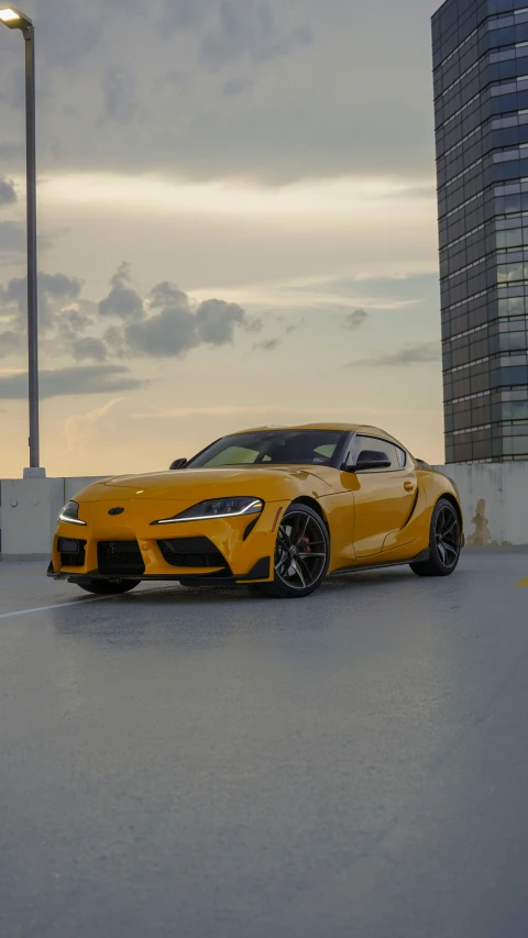 the yellow sports car has wheels and is parked in an empty lot