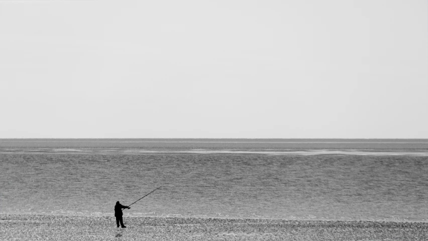 a person fishing on the beach during the day