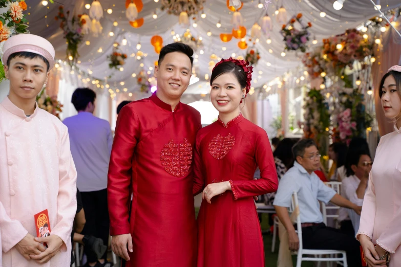 two smiling people in red are standing under decorations