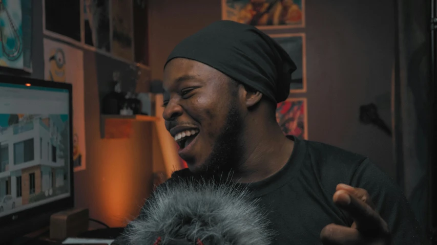 a black man smiling near a computer screen