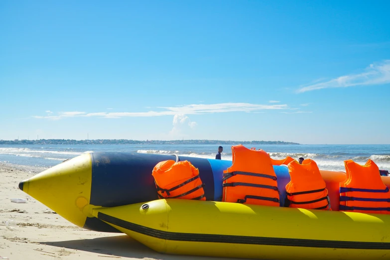 an orange life raft with yellow buoys on the beach