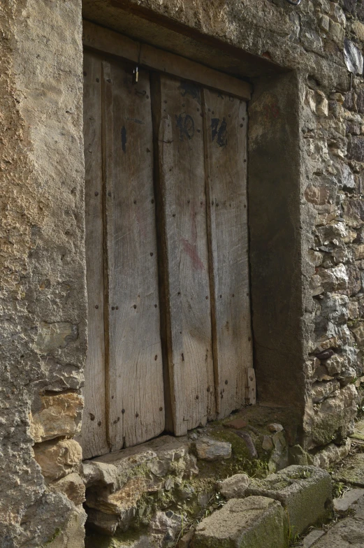 two wooden doors are open in an old stone building