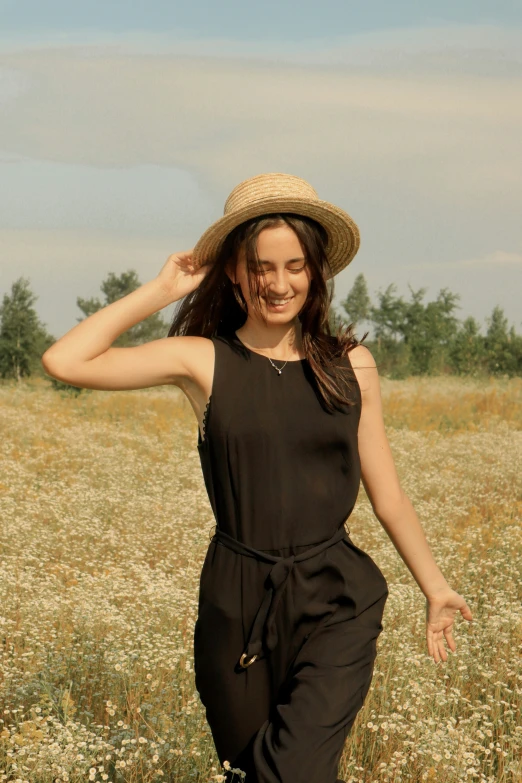 a young woman in a field wearing a hat