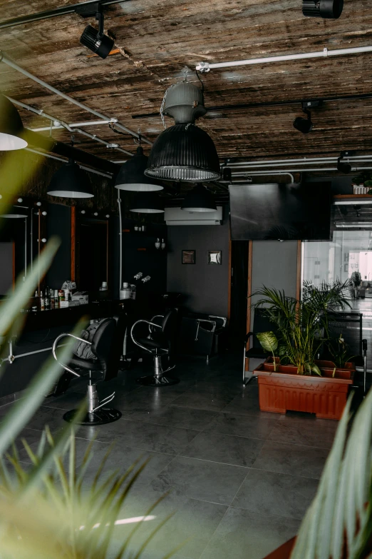 an empty salon with black furniture and hanging lamps