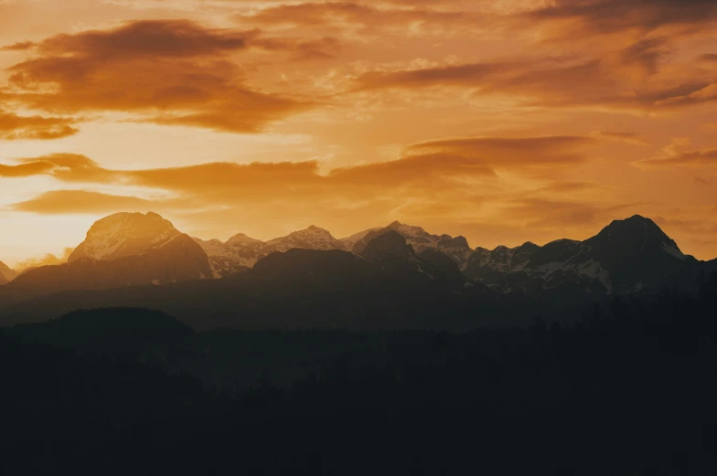 some mountains in a hazy sky with a large orange sky