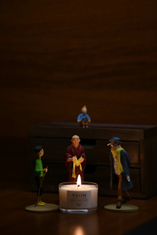 a bunch of toy figurines stand by a candle