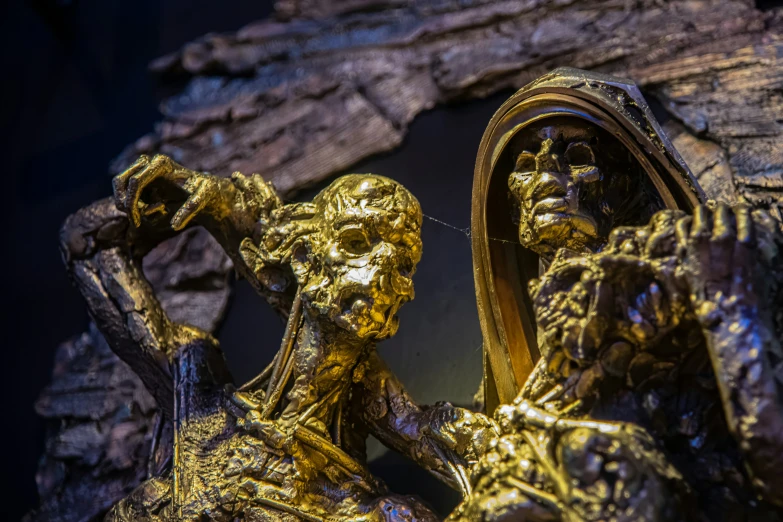 gold painted statues sit in front of a mirror