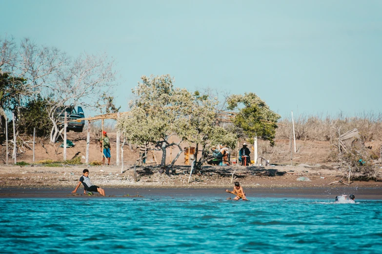 some people are sitting on the rocks near a lake