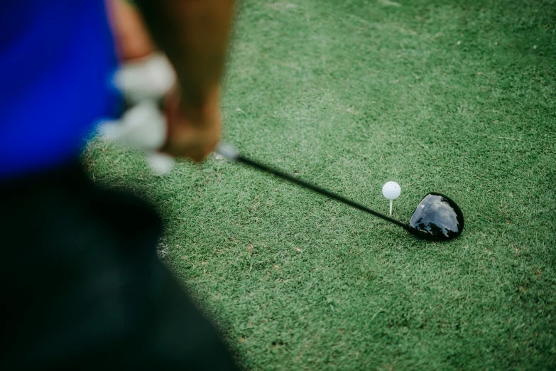 a person putting their golf ball into the hole